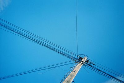 Low angle view of electricity pylon against clear blue sky