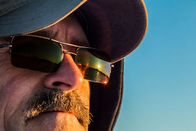 Close-up of mature man wearing sunglasses with reflection during sunset