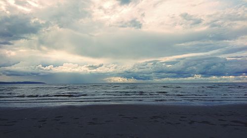 Scenic view of beach against dramatic sky