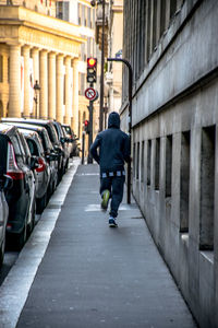Rear view of a man running on pedestrian walkway