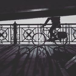 Silhouette people on bicycle against railing