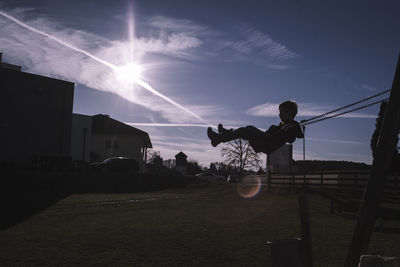 Silhouette man holding umbrella against sky