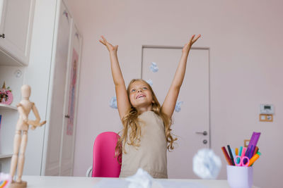 Happy schoolgirl throws up crumpled sheets of a school notebook