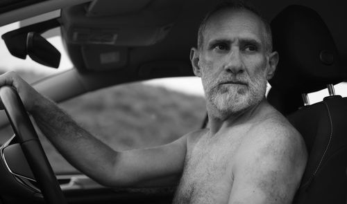 Monochrome of portrait of shirtless adult man in car