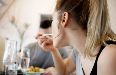 Close-up of young woman eating with man at home