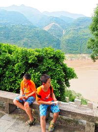 Rear view of people on mountain against trees