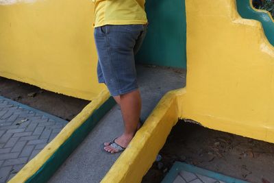 Low section of woman standing on yellow umbrella