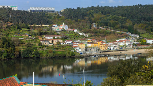 Scenic view of lake by townscape against trees