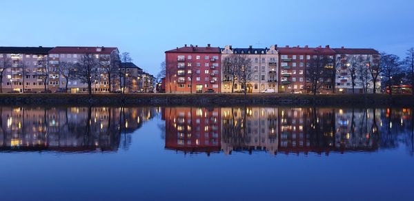 Reflection of illuminated buildings in lake against sky