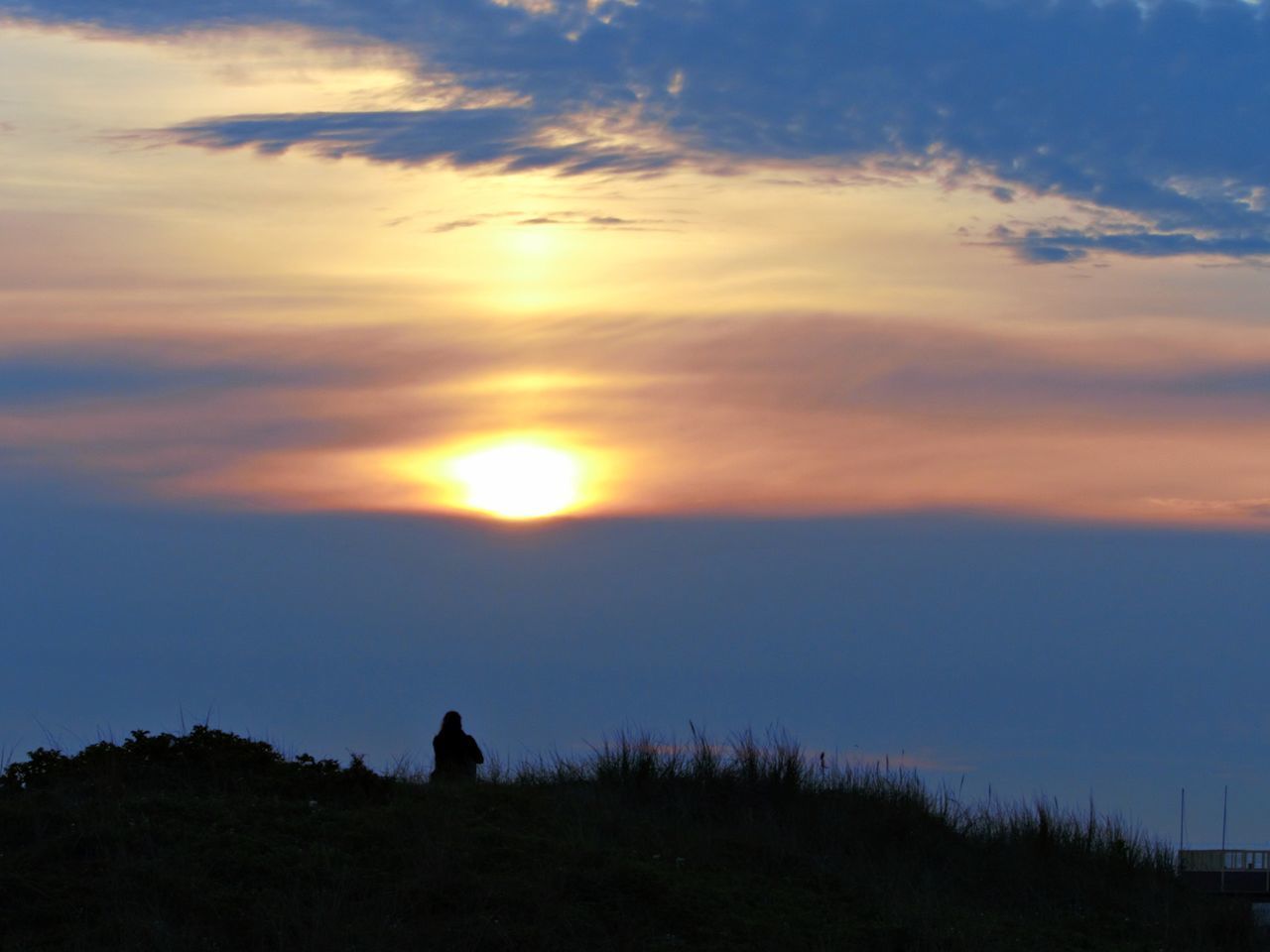 SILHOUETTE OF PEOPLE SITTING ON LAND AGAINST SKY DURING SUNSET