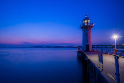 Lighthouse by sea against sky at night