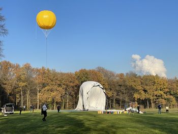 People on field by trees against sky