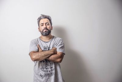 Portrait of man with arms crossed standing against gray background