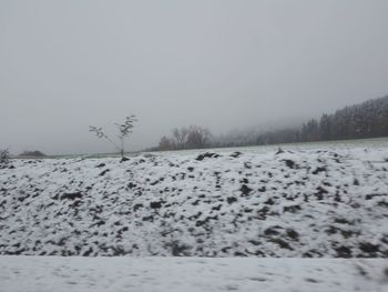 Snow covered land against clear sky during winter