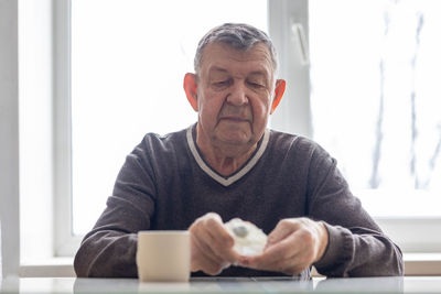 Portrait of elderly man. senior takes pills sitting at table