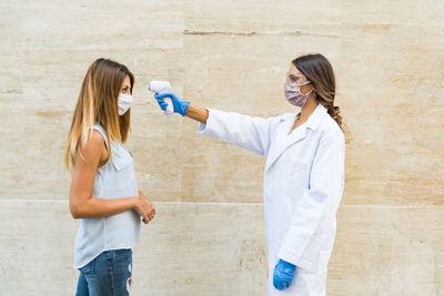 Doctor checking temperature of woman outdoors