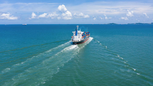 Shipping container sailing in sea against sky