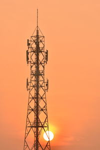 Low angle view of silhouette communications tower against sky during sunset