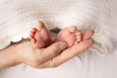 Cropped hand of baby on bed