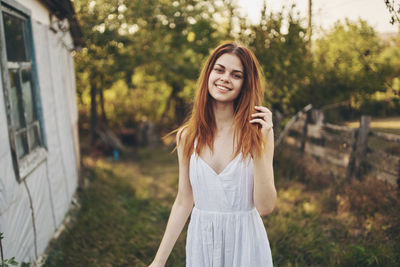 Portrait of smiling young woman standing against trees