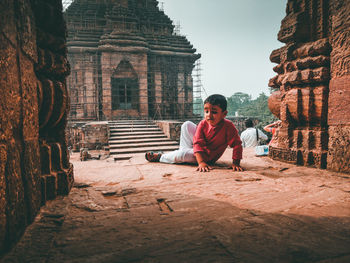 Full length of boy sitting outside temple
