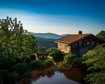 Buildings by river against sky