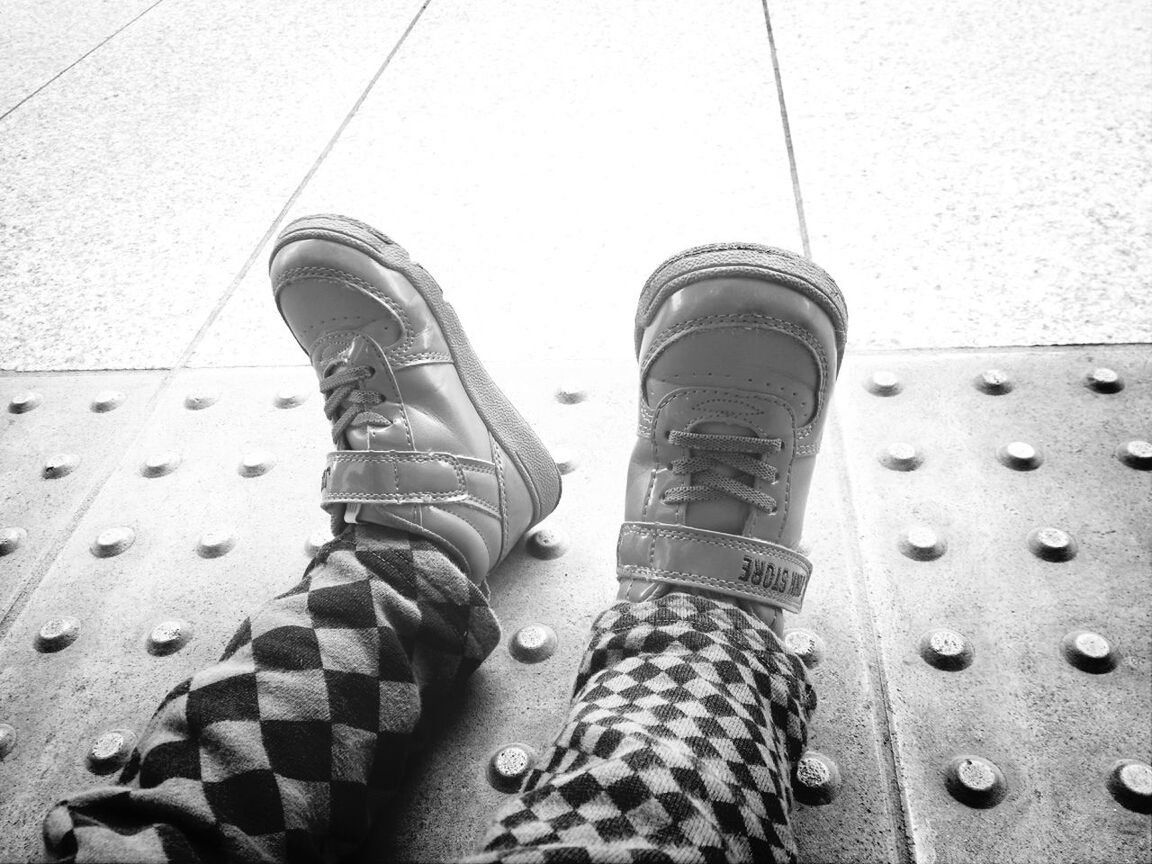 low section, shoe, person, high angle view, close-up, street, day, personal perspective, jeans, built structure, metal, outdoors, protection, architecture, footwear, part of, lifestyles