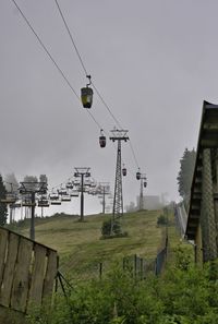 Low angle view of overhead cable cars against sky