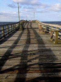 Wooden pier on sea against cloudy sky