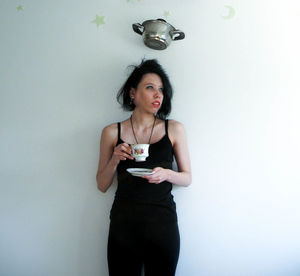 Portrait of young woman standing against white background