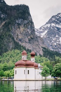 Lake by buildings against mountains