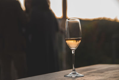 Close-up of wineglass on table at sunset with backlighting