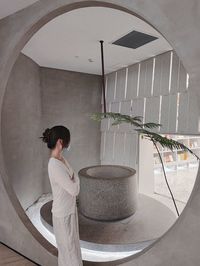 Side view of woman standing by potted plants