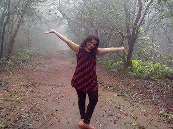 Full length of woman standing on tree trunk