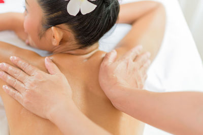 Cropped hands of masseuse giving massage to young woman relaxing at spa