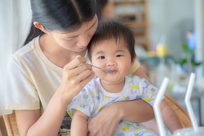 Mother feeding daughter at home