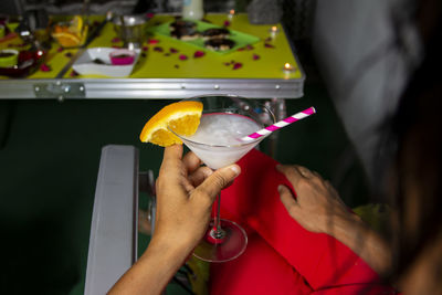 Happy romantic couple celebrating, holding glasses of cocktails with fruits and drinking straws. 