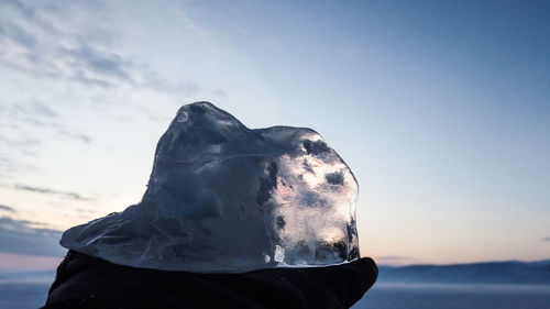 Close-up of person by sea against sky during winter