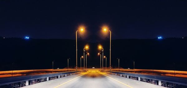 Illuminated light trails on road against sky at night