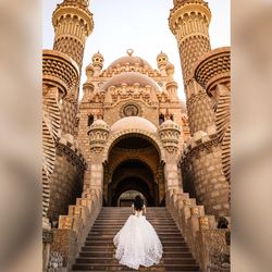 Rear view of woman visiting historic building against sky