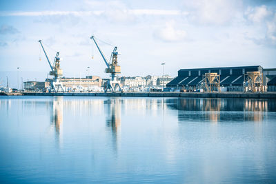 Cranes at harbor against sky