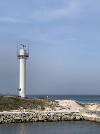 Lighthouse by sea against sky