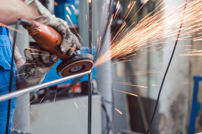 Midsection of man working on metal in factory