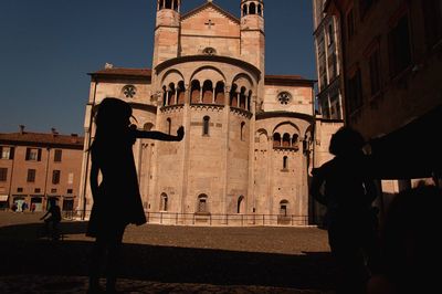 People in historic building against sky in city