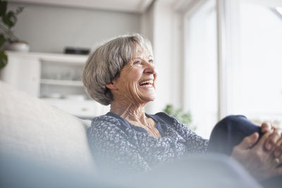 Portrait of laughing senior woman sitting on couch at home