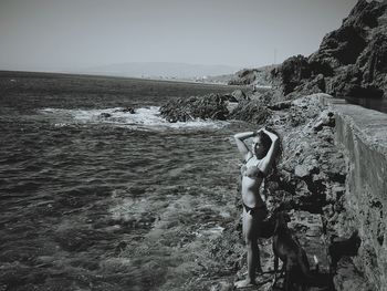 Rear view of woman photographing sea against clear sky