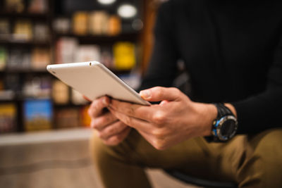 Midsection of man using small tablet