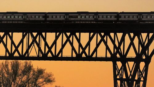 Low angle view of railway bridge against sky during sunset