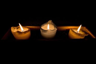 Close-up of lit candles in darkroom