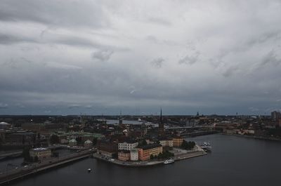 City at waterfront against cloudy sky